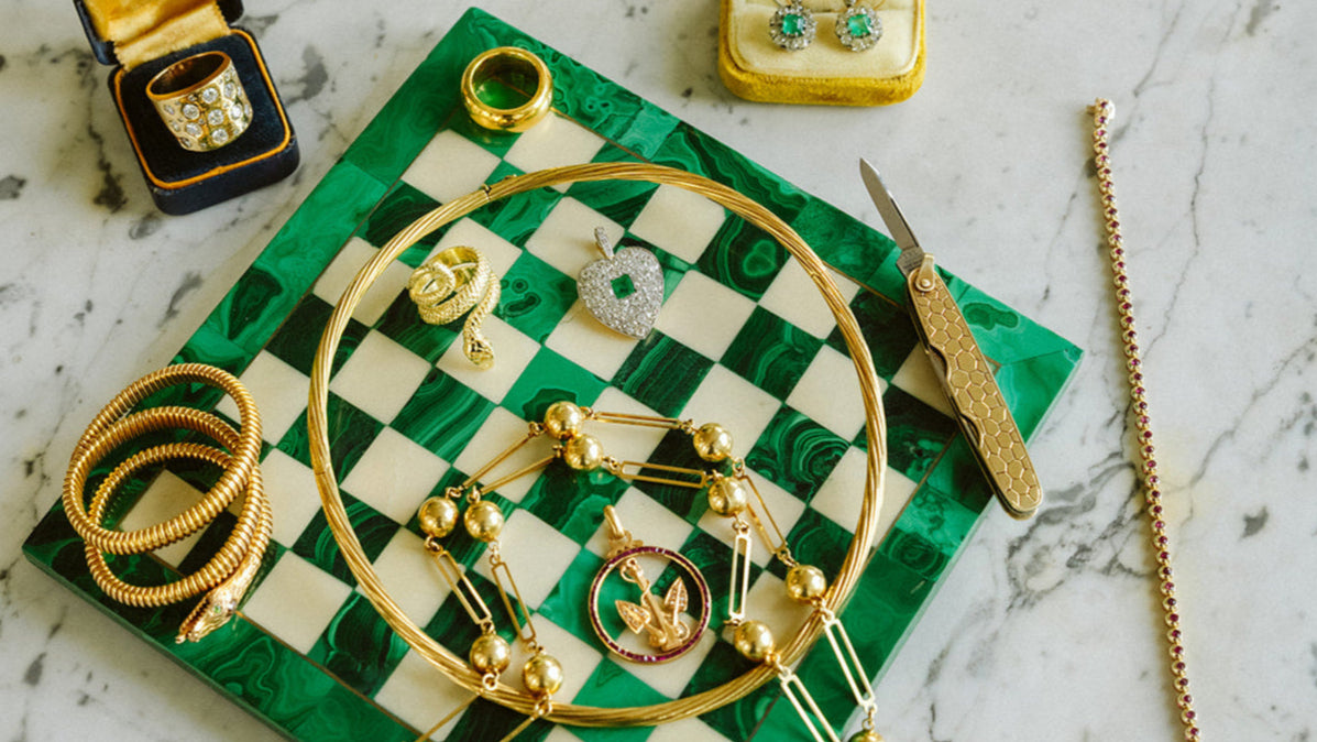 Display of vintage gold Cartier knife and assorted vintage fine gold jewelry with diamonds emeralds, and rubies